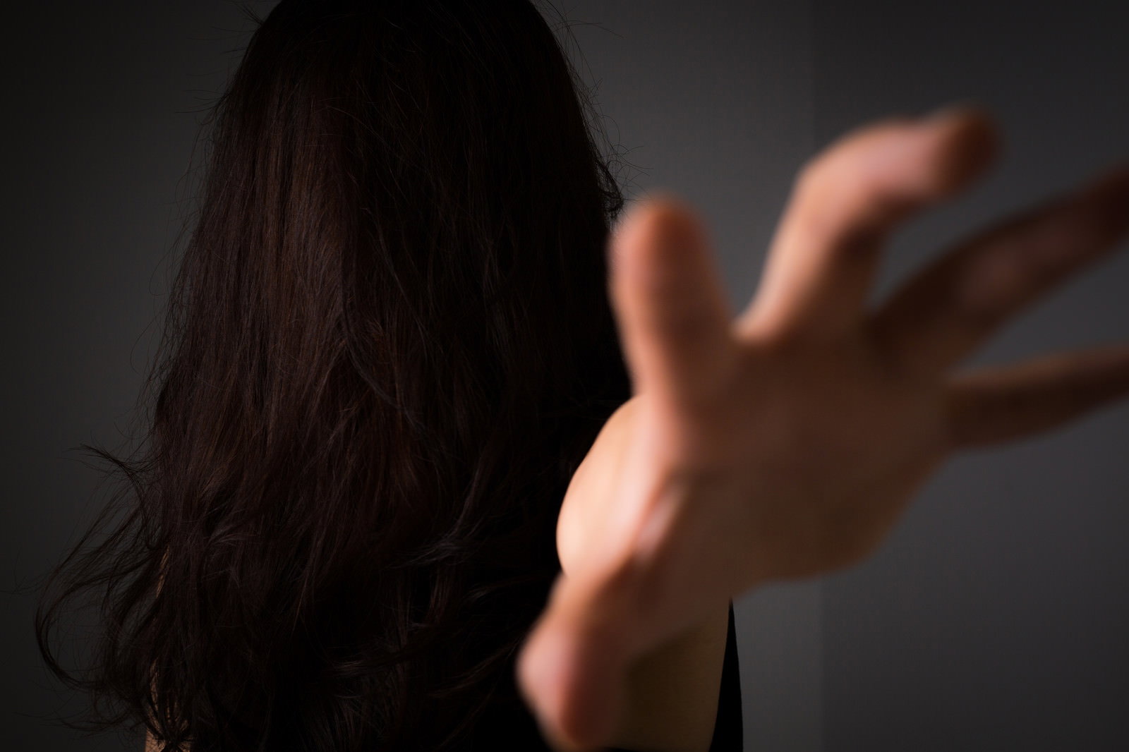 黒髪の女性が後ろ姿で手を前に突き出す、呪いをかけるような動作