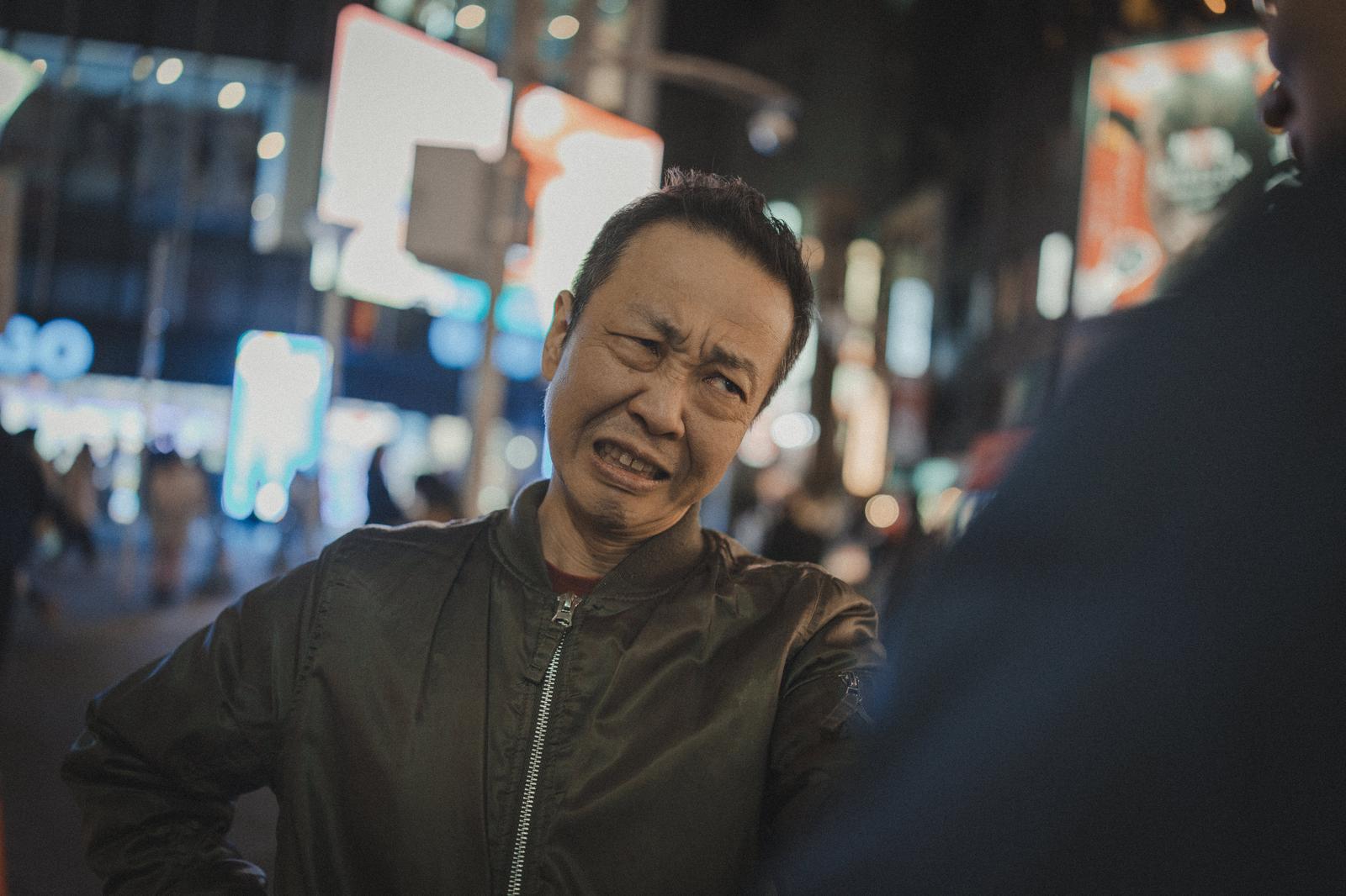An angry man in the street at night, frowning and clenching his teeth