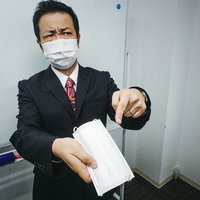 嫌な顔をしながらマスクを手渡しする会社員男性の写真