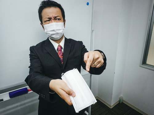 嫌な顔をしながらマスクを手渡しする会社員男性