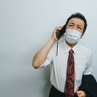 暑さで朦朧としながら会社に報告の電話をいれる外回り営業男性の写真