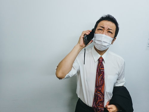 暑さで朦朧としながら会社に報告の電話をいれる外回り営業男性