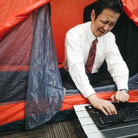 テントの中で要件定義書を作る社畜会社員のワーケーションの写真