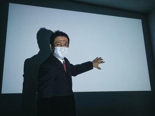 投影されながらプレゼンをはじめる上司
