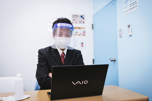 常に感染症対策を怠らない役員がフェイスシールドとマスクで業務に当たる