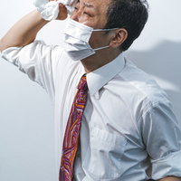 夏日にマスクをして外回りの営業マン、タオルで汗を拭くの写真