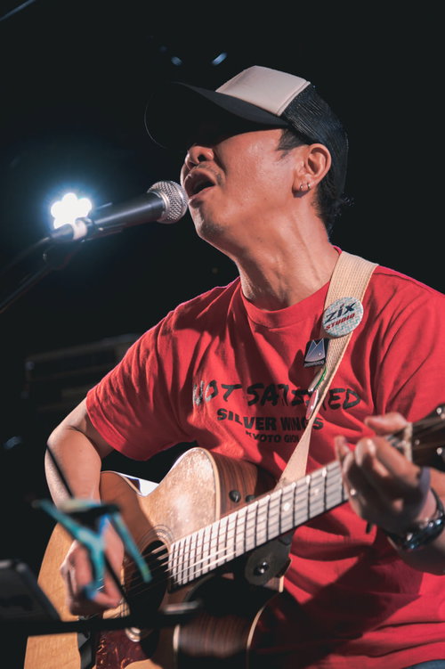 ライブステージで熱唱するアコースティックギターボーカルの男性