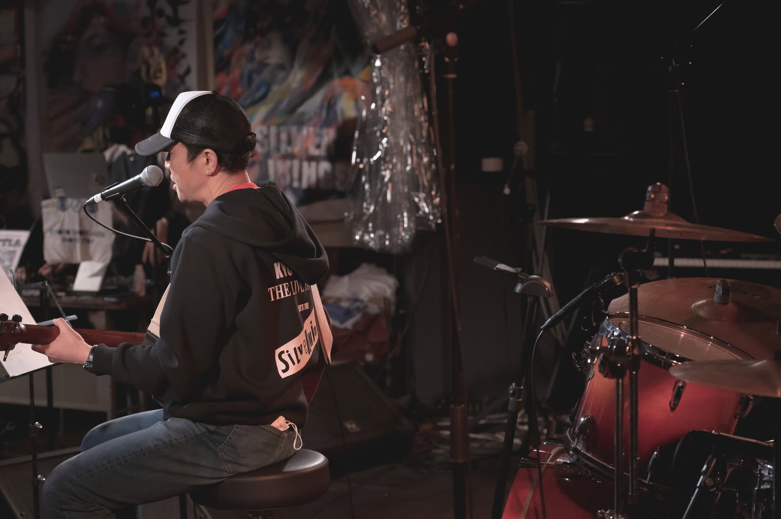 ライブハウスでアコースティックギターを演奏する男性ボーカルをステージ裏から撮影した様子［モデル：のせさん］