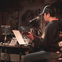 ステージで演奏するアコースティックギターの男性の写真