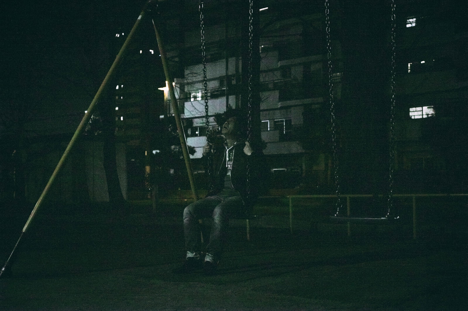 夜の公園でブランコに座りうなだれる中年男性［モデル：のせさん］