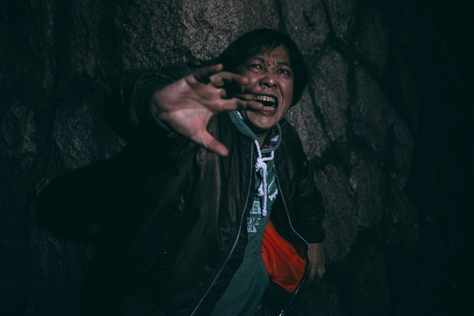 暗闇の中で恐怖に慄き、手を顔に当てて怯える男性［モデル：のせさん］