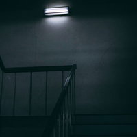 一人称視点で眺める仄暗い階段の踊り場と手すりの写真