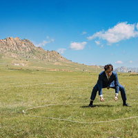 モンゴルの大草原でスーツ姿の男性が四股を踏む瞬間の写真