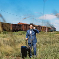 モンゴルの草原で貨物列車を背に通話するビジネスマンの写真