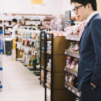 スーパーの売り場で商品を吟味する紺色スーツの男性の写真