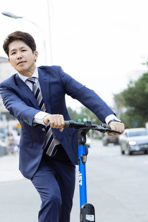 電動キックボードで通勤するビジネスマン スーツ姿