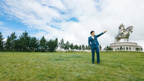 モンゴルの草原でチンギスハーン騎馬像を前に未来を指すビジネスマン