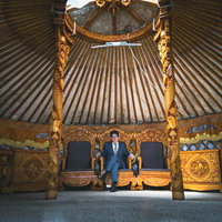 モンゴル伝統ゲル内部の金色装飾王座に座るスーツ姿の男性の写真