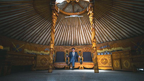 モンゴル伝統ゲル内部の金色装飾王座に座るスーツ姿の男性