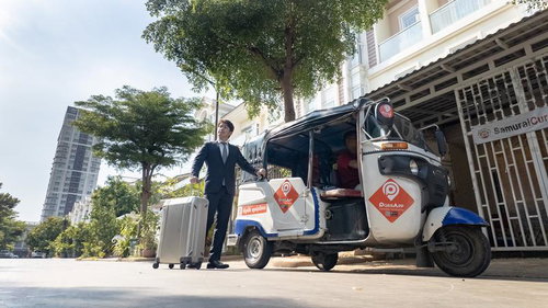 カンボジアで出張中のビジネスマン、キャリーケースを手に歩く