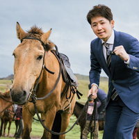 馬の手綱を握り締め、モンゴルの草原で決意を新たにするビジネスマンの写真