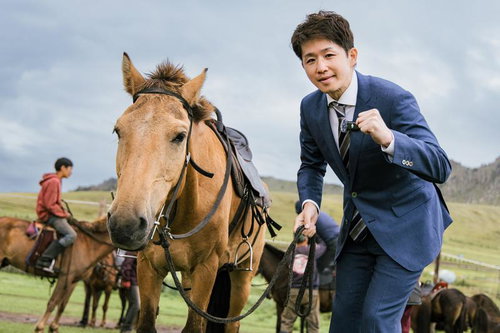 馬の手綱を握り締め、モンゴルの草原で決意を新たにするビジネスマン
