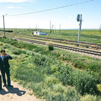 モンゴルの広大な草原と鉄道を背に商談するビジネスマンの写真