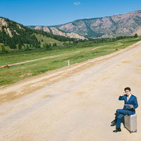 馬が行き交う荒れた道端で仕事をこなすモンゴルのビジネスマンの写真