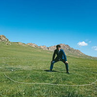 草原で力強くしこを踏むスーツ姿の男性、モンゴルの大自然を背景にの写真