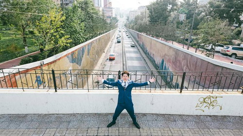 モンゴルの都会を背景に両手を広げてポージングする男性