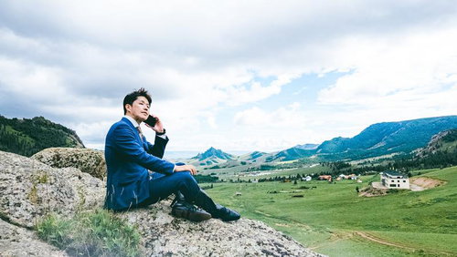 広大なモンゴルの草原を見渡しながら通話するビジネスマン