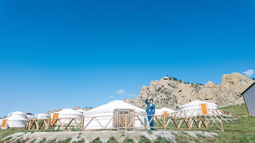 モンゴルの草原に並ぶゲルとスーツ姿の男性