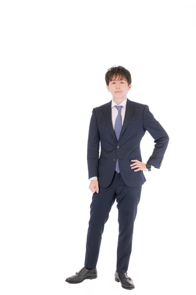 紺色スーツと青いネクタイを着た男性ビジネスマンの立ち姿ポートレート［モデル：野崎繁裕］