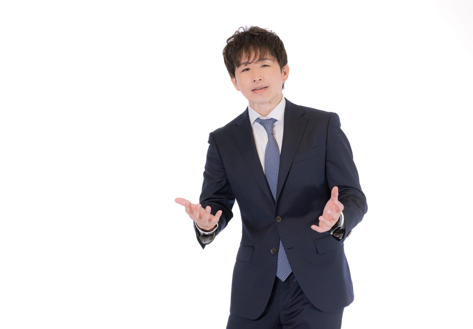 スーツ姿でジェスチャーを交えながら説明する男性［モデル：野崎繁裕］