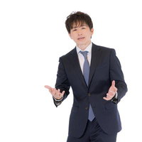 M&Aのメリットを説明するスーツ姿の男性講師の写真