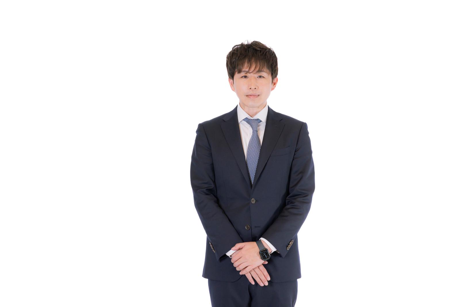 紺色スーツを着たM&Aアドバイザーの男性が正面に立つ［モデル：野崎繁裕］