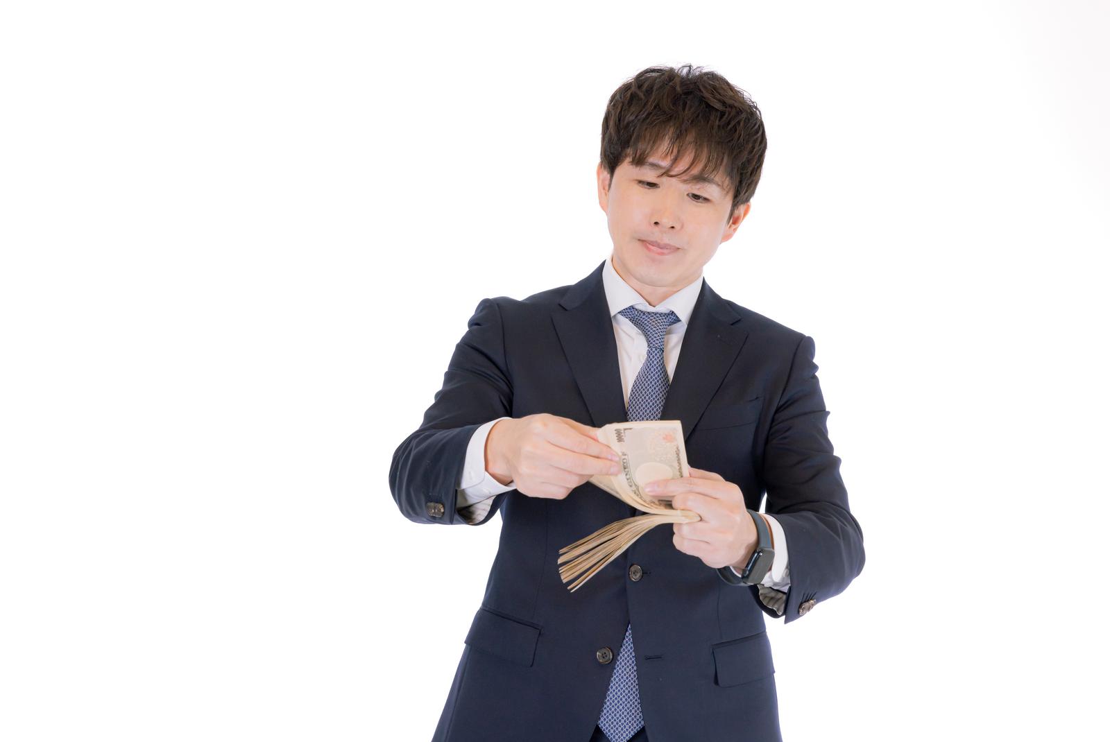 契約金の現金を数える紺色スーツ姿のM&Aアドバイザー［モデル：野崎繁裕］