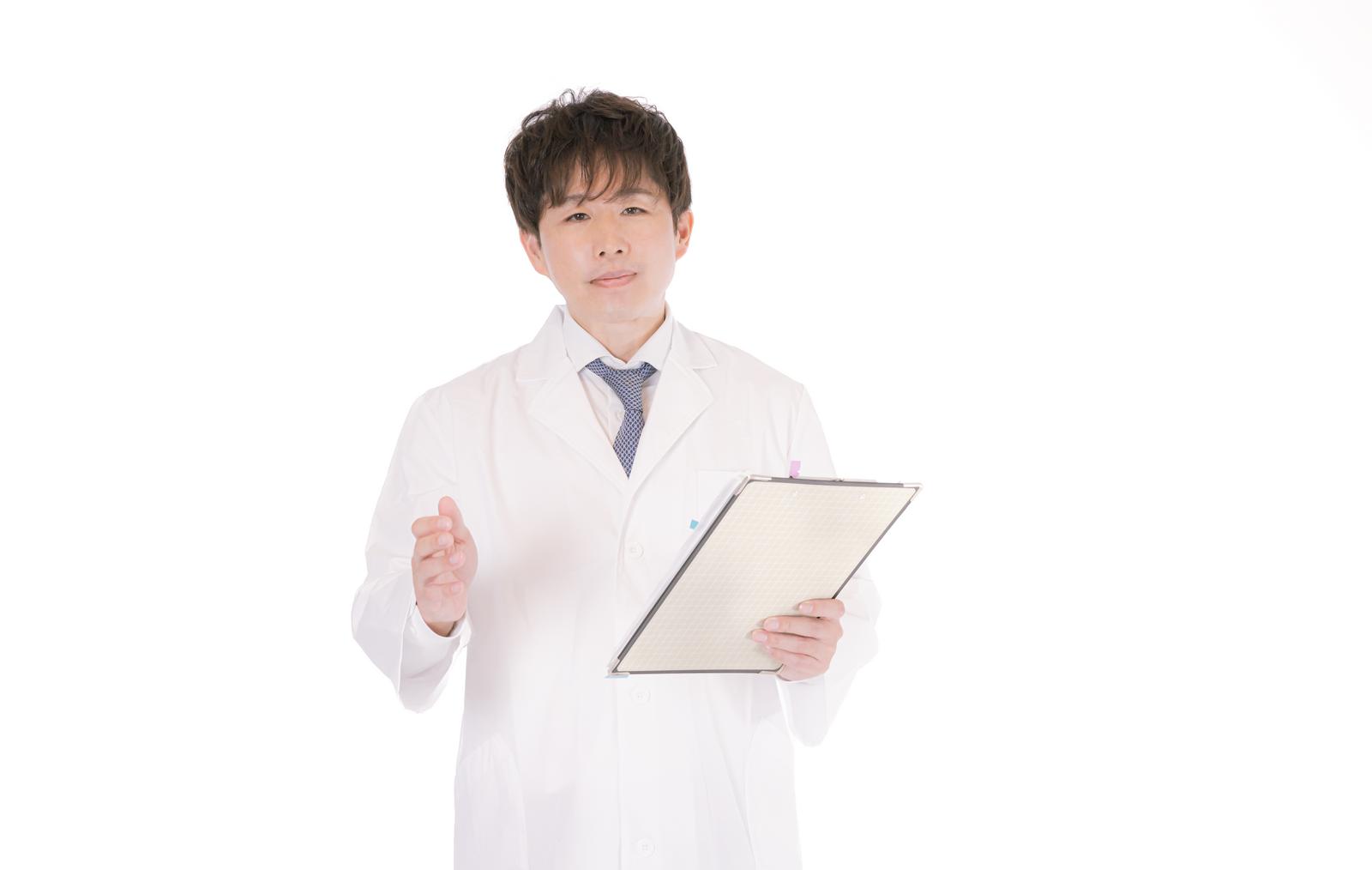 クリップボードを持つ白衣姿の男性医師［モデル：野崎繁裕］