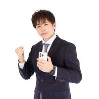 スマートフォンを持ってガッツポーズするM&Aアドバイザーの男性の写真