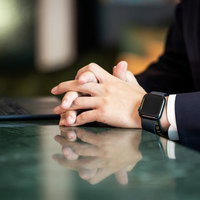 ガラステーブルで手を組み考える紺色スーツの男性の写真