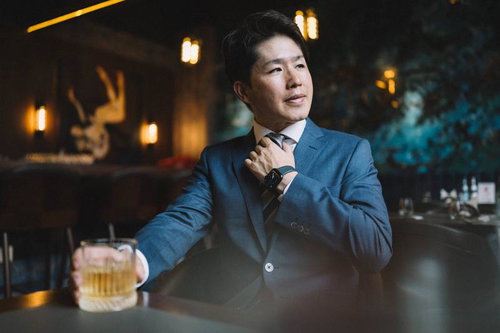 ウイスキーを片手にネクタイを直すビジネスマン