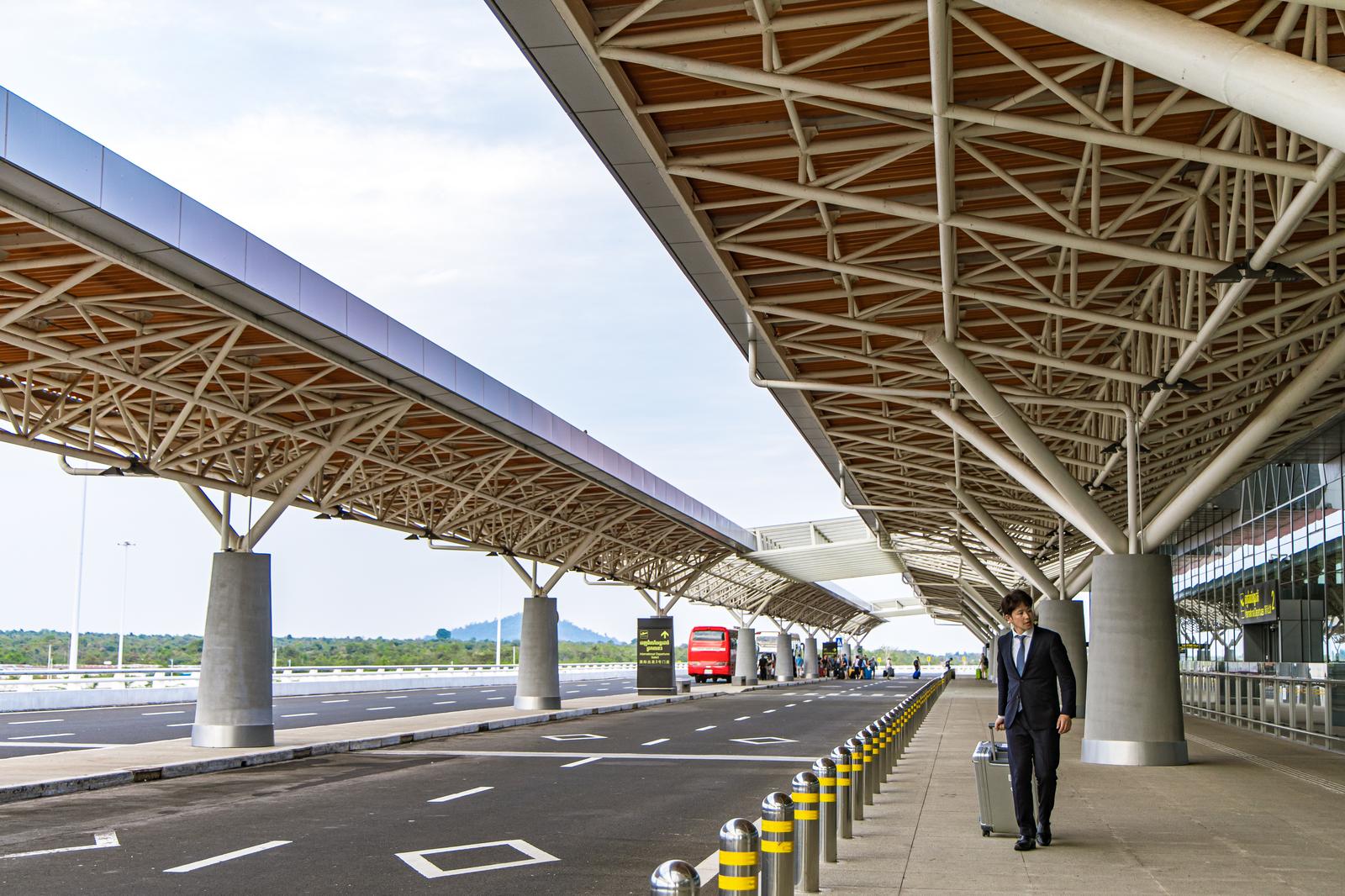 A man in a suit walking with a carry-on bag in an airport terminal