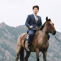馬上のスーツ姿で颯爽と進むビジネスマン、山道を乗馬で移動の写真