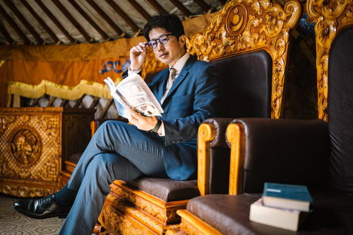 豪華なゲル内の椅子で新聞を読むM&Aアドバイザーの出張