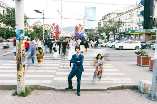 ノミンデパート（モンゴル）前の混雑した交差点で立ち尽くす会社員