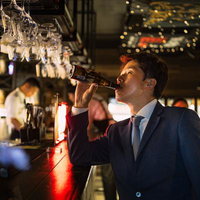 BARカウンターでビールを飲む会社員の夜間の憩いの写真