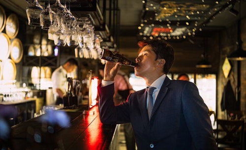 BARカウンターでビールを飲む会社員の夜間の憩い