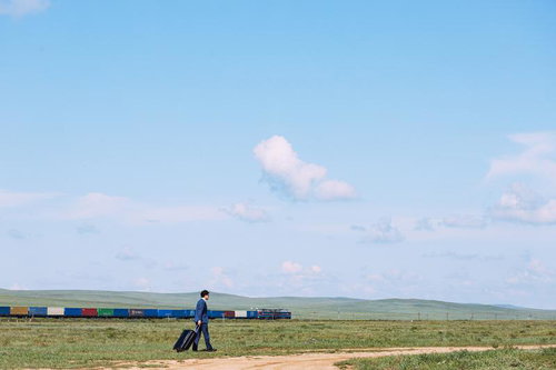 広大なモンゴルの草原を歩くビジネスマンと貨物列車