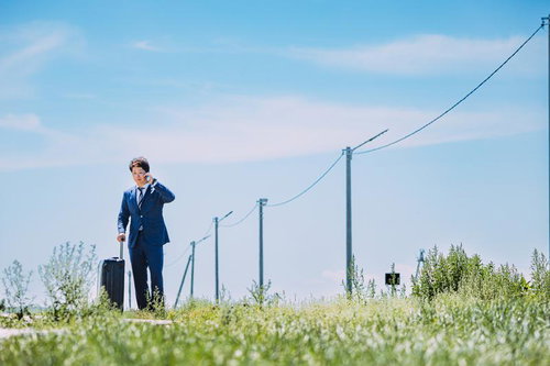 モンゴルの草原で電話をかける紺スーツのビジネスマン