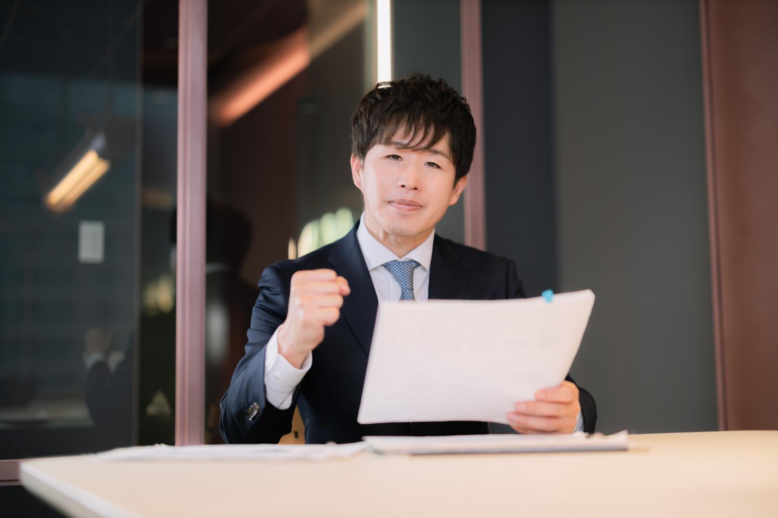 資料を持ちながら提案するM&Aアドバイザーの男性［モデル：野崎繁裕］